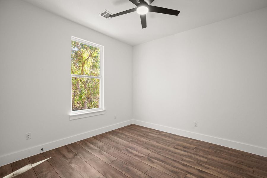 Unfurnished room featuring dark wood-type flooring and a ceiling fan
