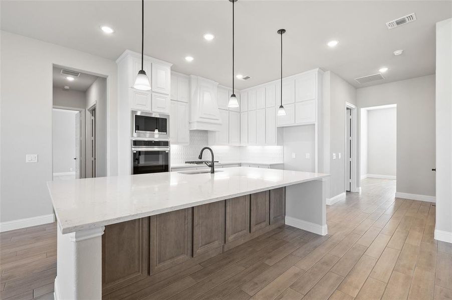 Kitchen with tasteful backsplash, white cabinetry, appliances with stainless steel finishes, light wood finished floors, and recessed lighting