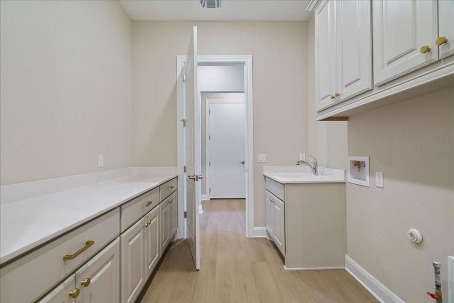 This laundry room has everything you could need - ample storage space, plenty of counter space, a sink, and direct access to one of two walk-in closets in the owner's suite.