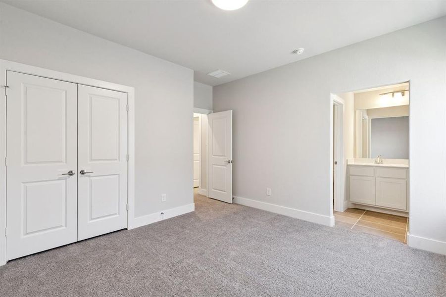 Unfurnished bedroom featuring light colored carpet, a closet, and ensuite bath Unfurnished bedroom featuring light colored carpet, a closet, and ensuite bath