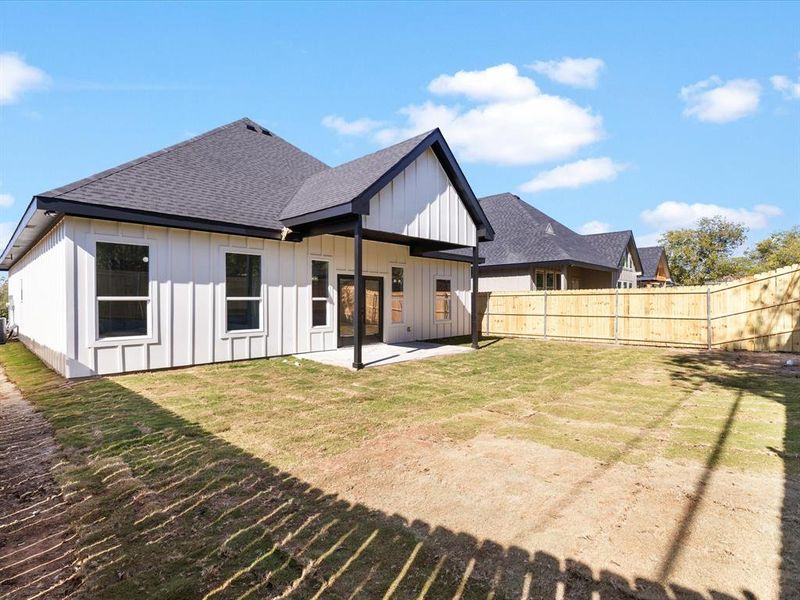 Back of house featuring a shingled roof, a patio area, and board and batten siding