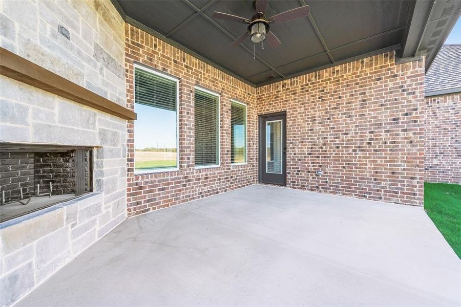 View of patio / terrace with ceiling fan and an outdoor stone fireplace