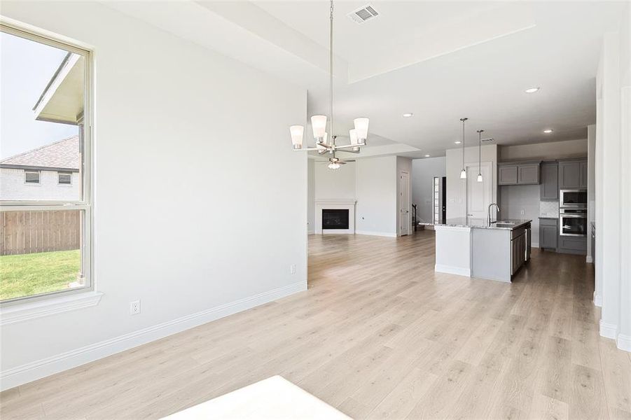 Kitchen featuring an island with sink, hanging light fixtures, sink, light wood-type flooring, and gray cabinets