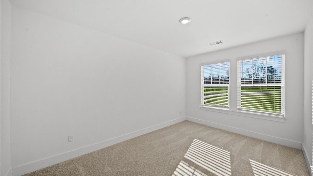 Notable bedroom offering soft carpet, a walk-in closet, and expansive windows overlooking the yard in Arden, NC