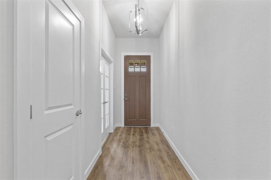 Doorway featuring an inviting chandelier and hardwood / wood-style floors