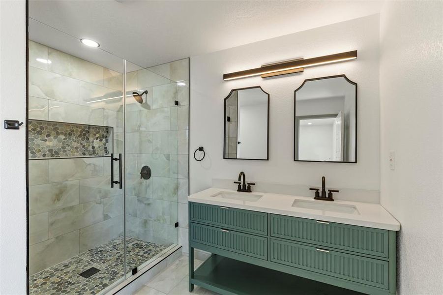 Bathroom with double vanity, a shower stall, and recessed lighting