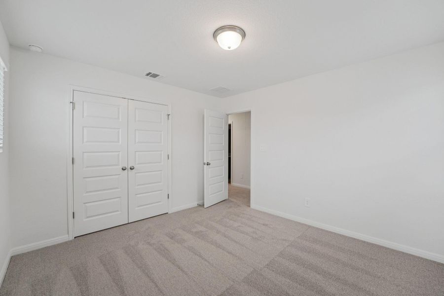 Unfurnished bedroom with light carpet and a closet