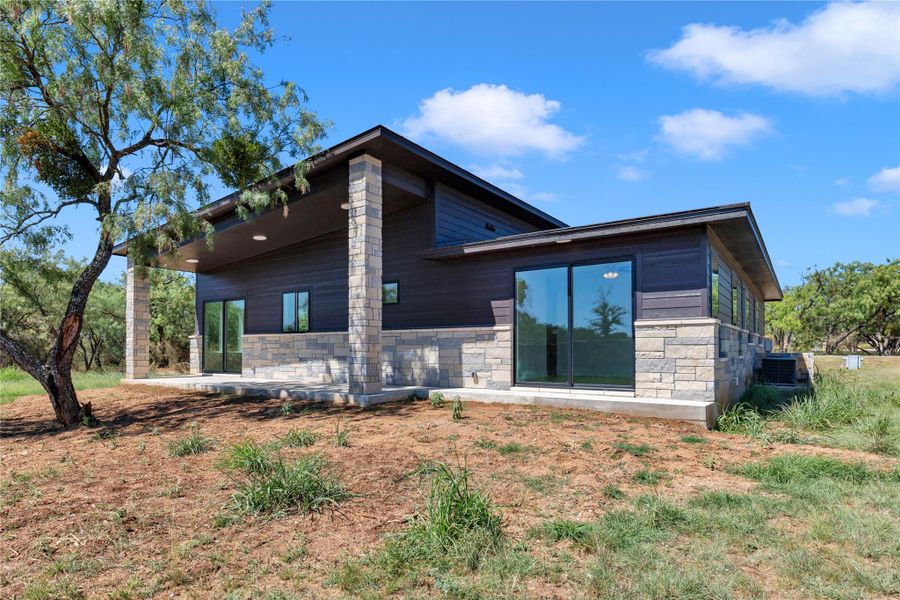 Bold stone pillars support a deep overhang alongside modern sliding glass doors.