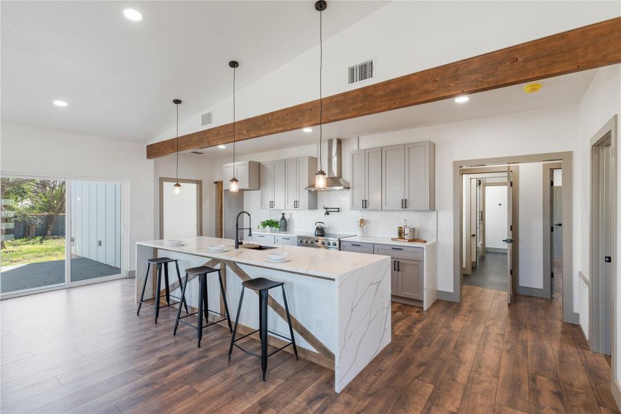Kitchen with dark wood-style floors, visible vents, a sink, wall chimney range hood, and backsplash