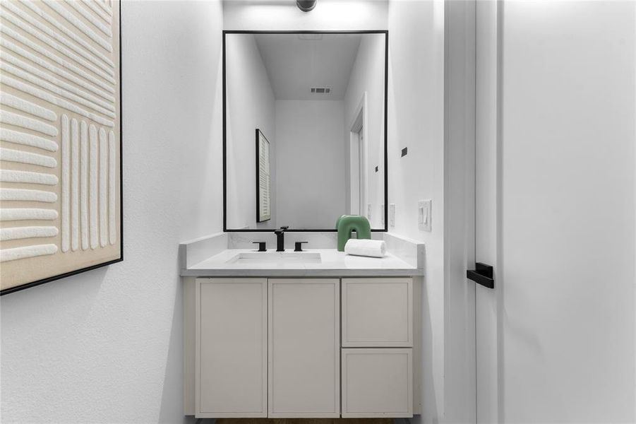 Modern bathroom vanity featuring a light-toned cabinet, integrated sink, and stone-finish countertop Modern bathroom vanity featuring a light-toned cabinet, integrated sink, and stone-finish countertop