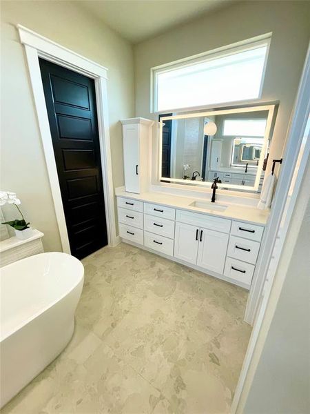 Master bathroom with vanity and a soaking tub