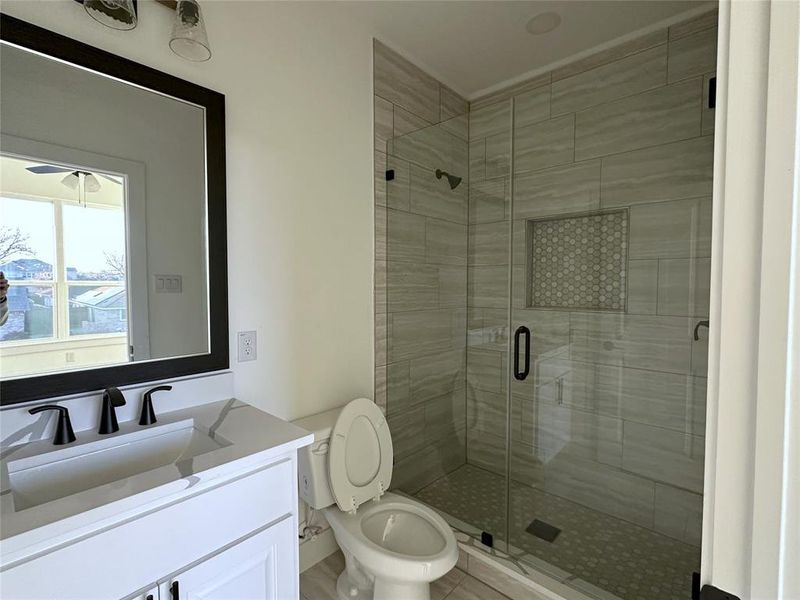 Bathroom featuring vanity, toilet, and a shower with shower door