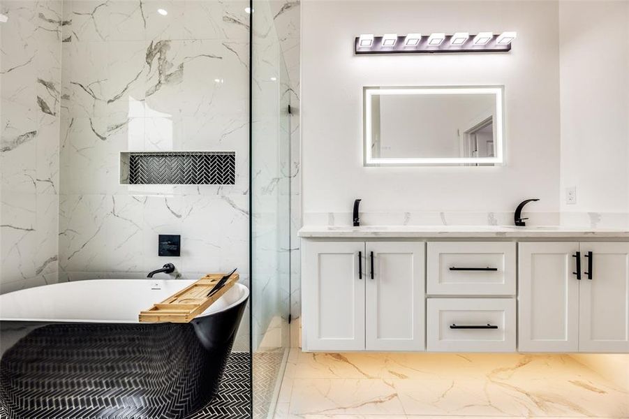 Bathroom featuring double vanity, a freestanding bath, light marble finish flooring, and a marble finish shower Bathroom featuring double vanity, a freestanding bath, light marble finish flooring, and a marble finish shower