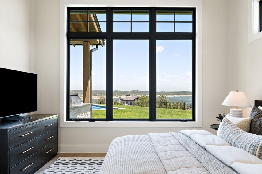 Bedroom with a water view, multiple windows, and light wood-style flooring