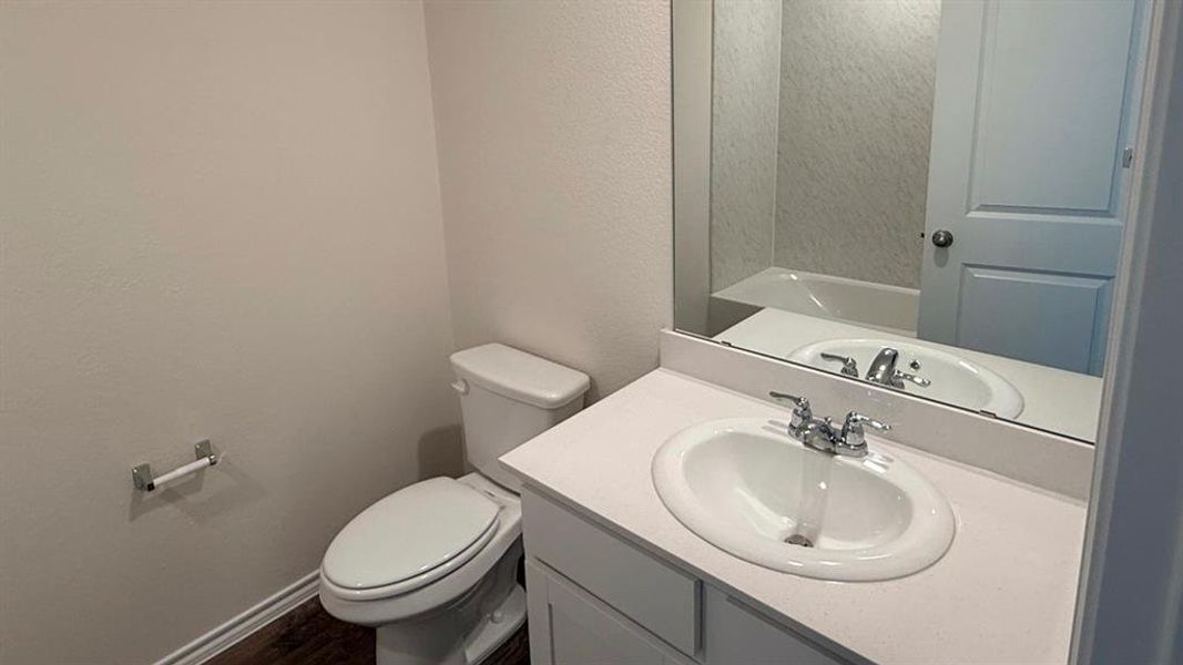 Bathroom with vanity, a textured wall, and dark wood-style flooring Bathroom with vanity, a textured wall, and dark wood-style flooring