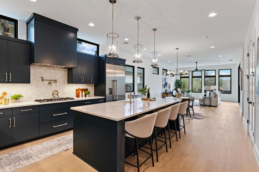 Kitchen with dark cabinetry, built in refrigerator, recessed lighting, and light countertops