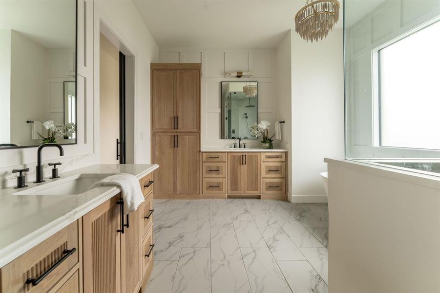 Bathroom featuring two vanities, light marble finish flooring, a stall shower, a chandelier, and a soaking tub Bathroom featuring two vanities, light marble finish flooring, a stall shower, a chandelier, and a soaking tub