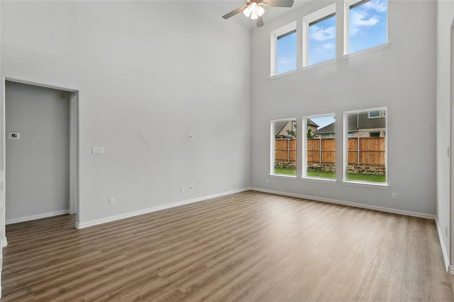 Empty room featuring a high ceiling, ceiling fan, wood finished floors, and baseboards Empty room featuring a high ceiling, ceiling fan, wood finished floors, and baseboards