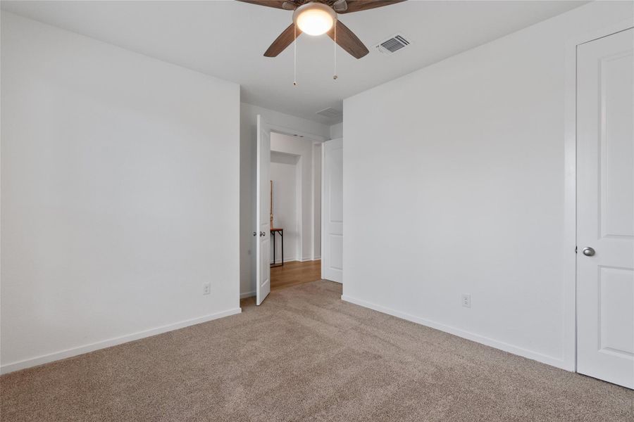 A well-lit bedroom with carpeting and a ceiling fan