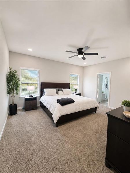 Spacious bedroom featuring light-colored walls, warm-toned carpeting, and a vaulted ceiling