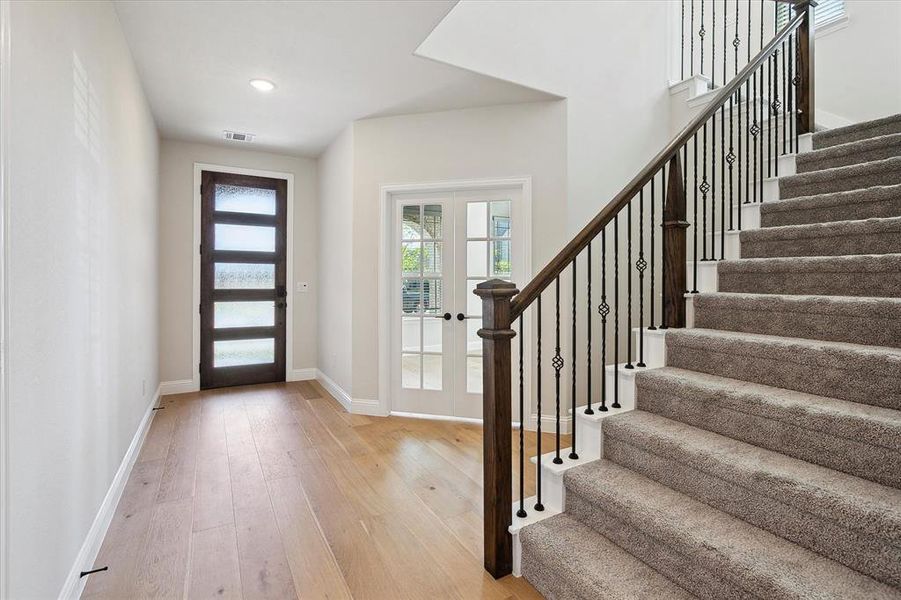 Entryway with french doors, light wood-style flooring, stairs, and baseboards