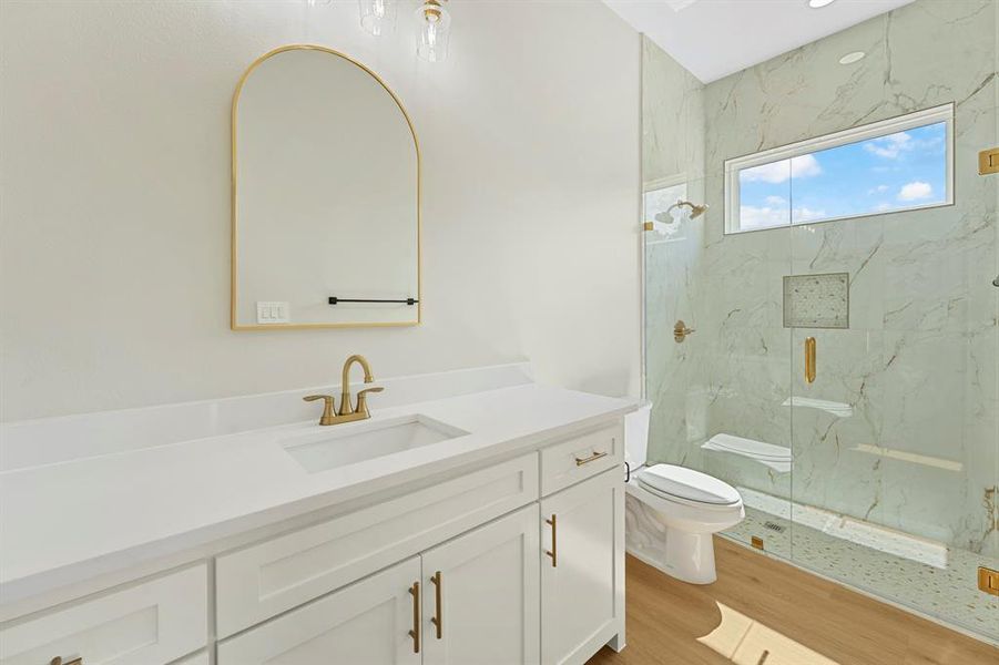 Full bathroom with a marble finish shower, vanity, and light wood-type flooring