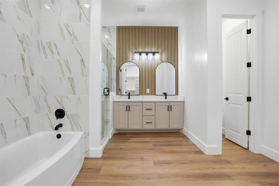 Bathroom with double vanity, a bath, light wood finished floors, and a stall shower