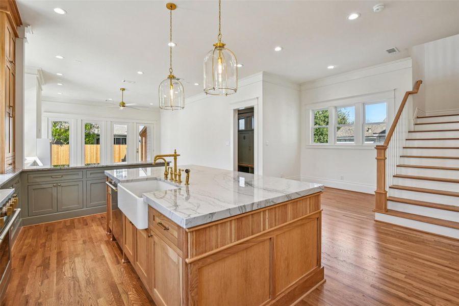 The kitchen looking into the breakfast area. The kitchen island is a quartzite set atop a stained white oak base with a farm sink and traditional plumbing fixtures. The kitchen looking into the breakfast area. The kitchen island is a quartzite set atop a stained white oak base with a farm sink and traditional plumbing fixtures.