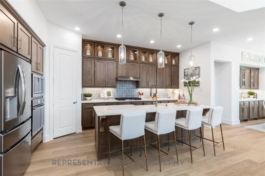 Kitchen featuring decorative backsplash, stainless steel appliances, a kitchen bar, dark brown cabinets, and recessed lighting