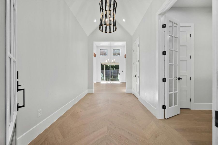 Corridor featuring light parquet floors, high vaulted ceiling, and an inviting chandelier