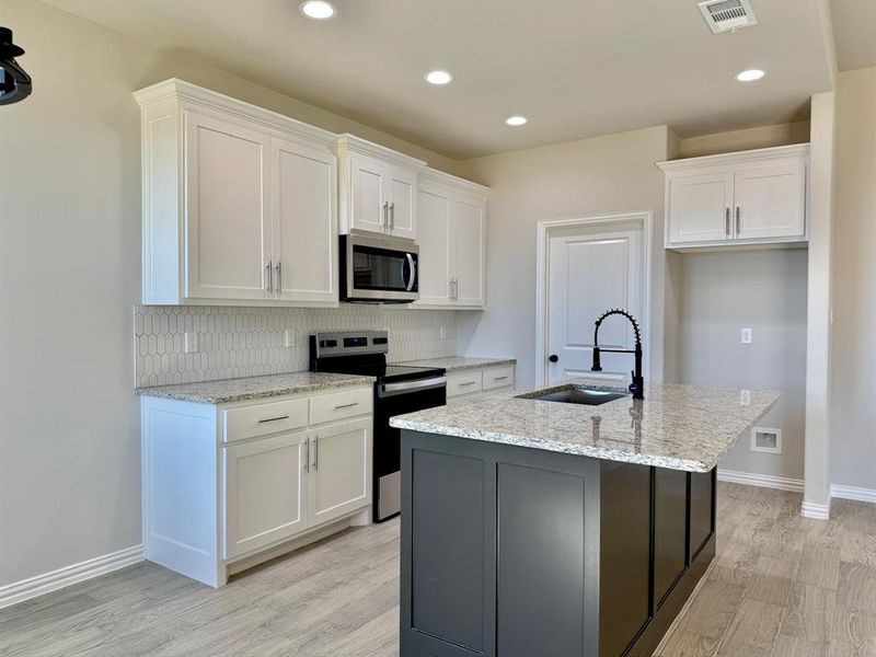 Kitchen featuring white cabinetry, appliances with stainless steel finishes, sink, and a center island with sink