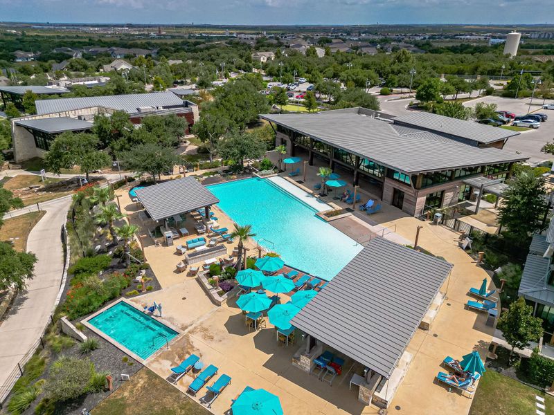 An aerial perspective reveals a sparkling outdoor pool and a separate spa tub, surrounded by inviting lounge areas and community buildings. An aerial perspective reveals a sparkling outdoor pool and a separate spa tub, surrounded by inviting lounge areas and community buildings.