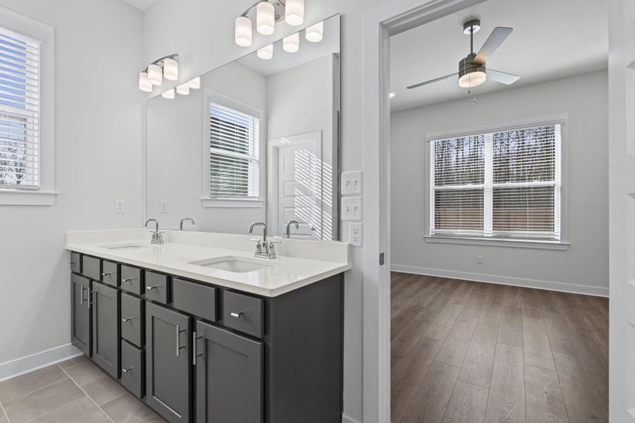 Full bath with double vanity, healthy amount of natural light, and a ceiling fan