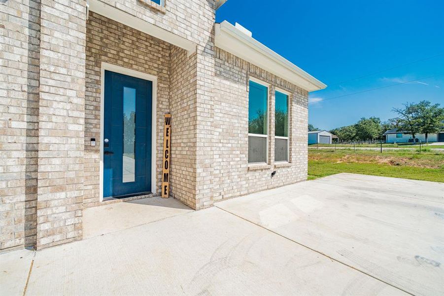 Entrance to property featuring brick siding and a patio Entrance to property featuring brick siding and a patio