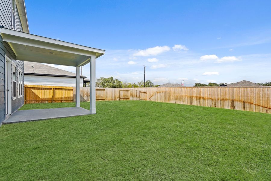A fenced in yard with a building and a wood fence.