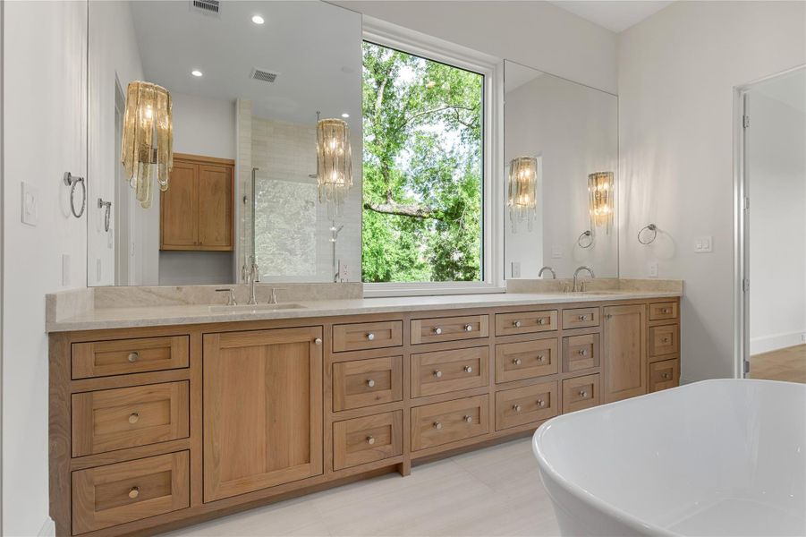 Hudson Valley Lighting, Taj Mahal quartzite, and tree views in the primary bath offer spa-like setting to recharge from the day.