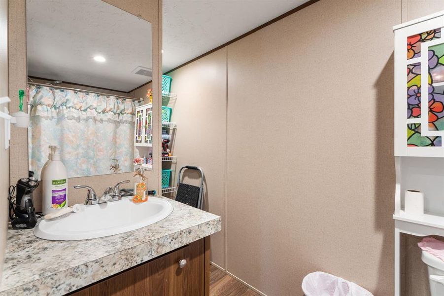 Bathroom with visible vents, vanity, a shower with curtain, and wood finished floors Bathroom with visible vents, vanity, a shower with curtain, and wood finished floors