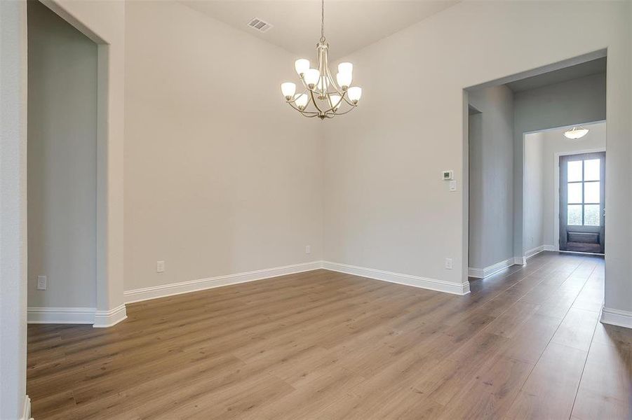 Empty room with a chandelier and hardwood / wood-style flooring