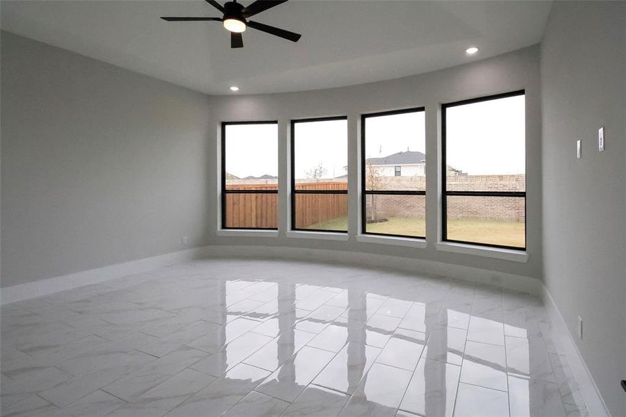 Unfurnished room featuring a wealth of natural light and ceiling fan