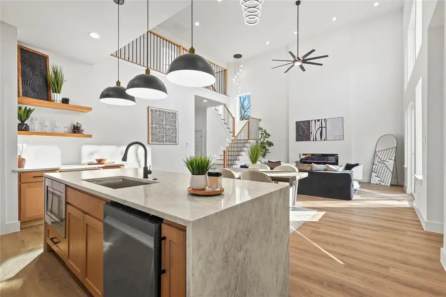 Kitchen featuring light stone countertops, pendant lighting, open floor plan, light wood-type flooring, and open shelves