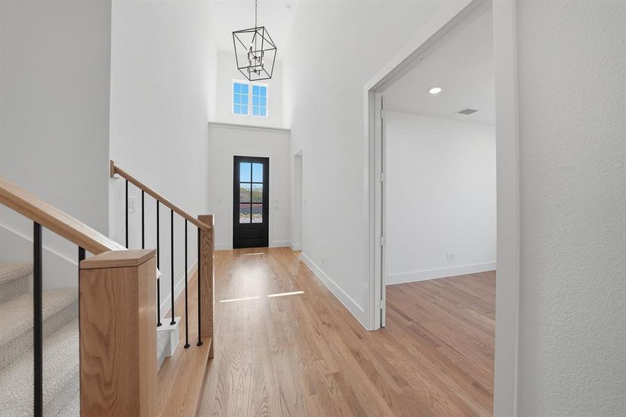 Foyer with light wood-style floors, a high ceiling, a chandelier, recessed lighting, and stairway Foyer with light wood-style floors, a high ceiling, a chandelier, recessed lighting, and stairway