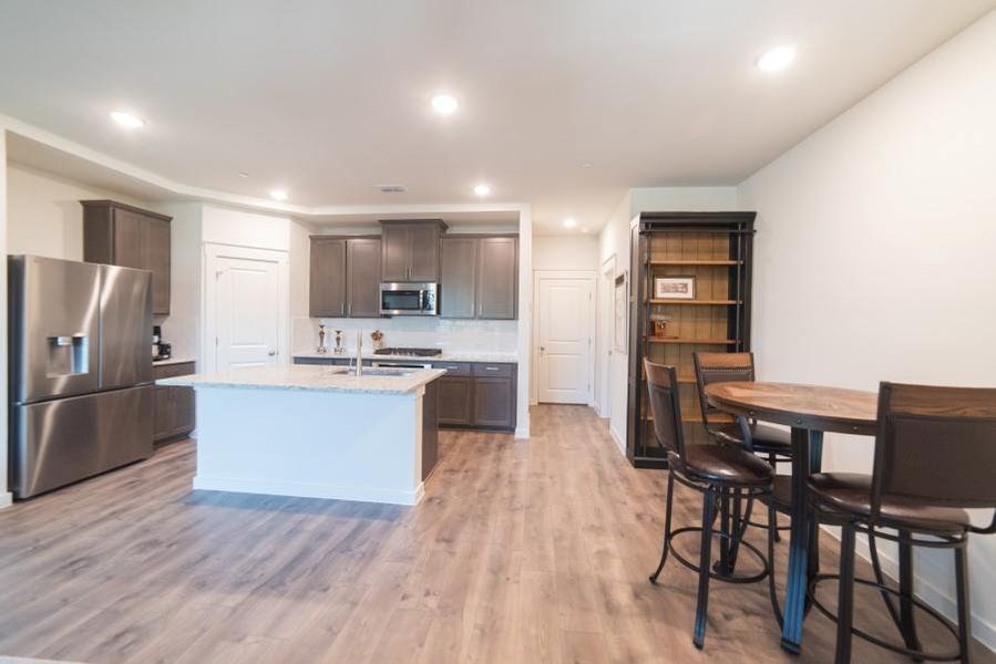 Kitchen featuring appliances with stainless steel finishes, dark brown cabinets, recessed lighting, tasteful backsplash, and light wood-style floors