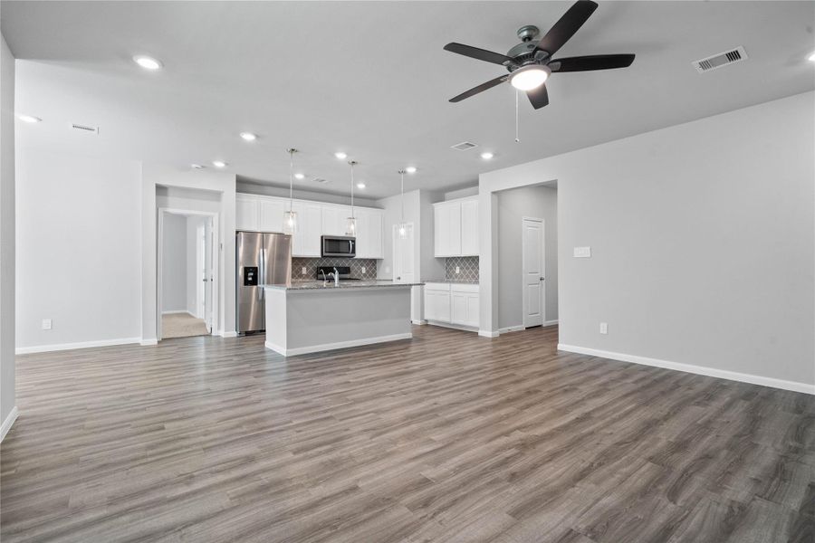 This expansive view from Great Room showcases a seamless, open-concept layout that creates a warm and inviting path for guests, drawing the eye toward the hallway leading to the secondary bedrooms and entry. This expansive view from Great Room showcases a seamless, open-concept layout that creates a warm and inviting path for guests, drawing the eye toward the hallway leading to the secondary bedrooms and entry.