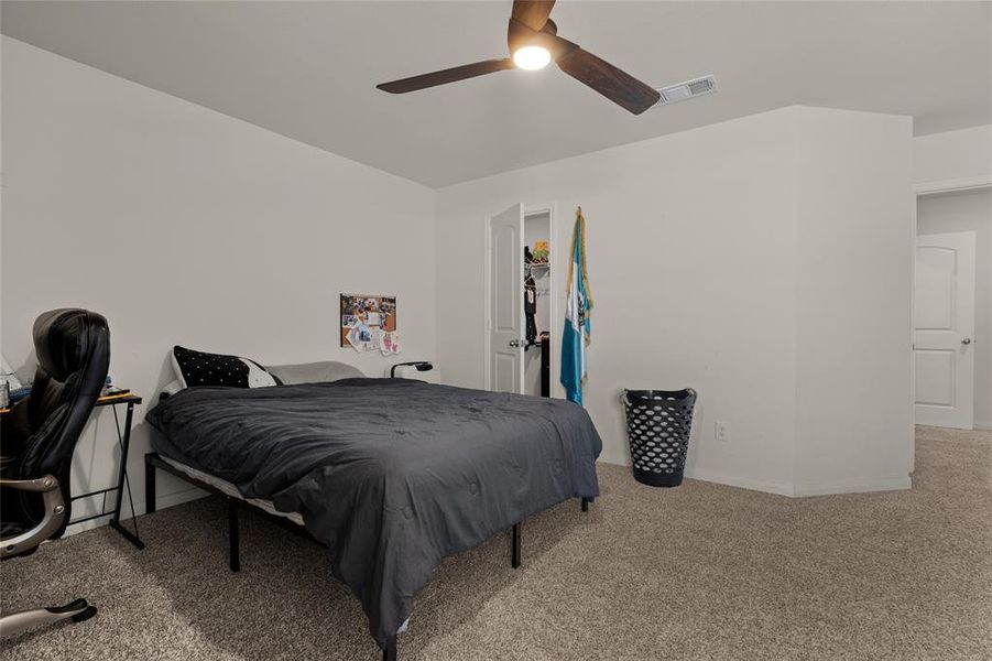 Carpeted bedroom with a spacious closet and ceiling fan