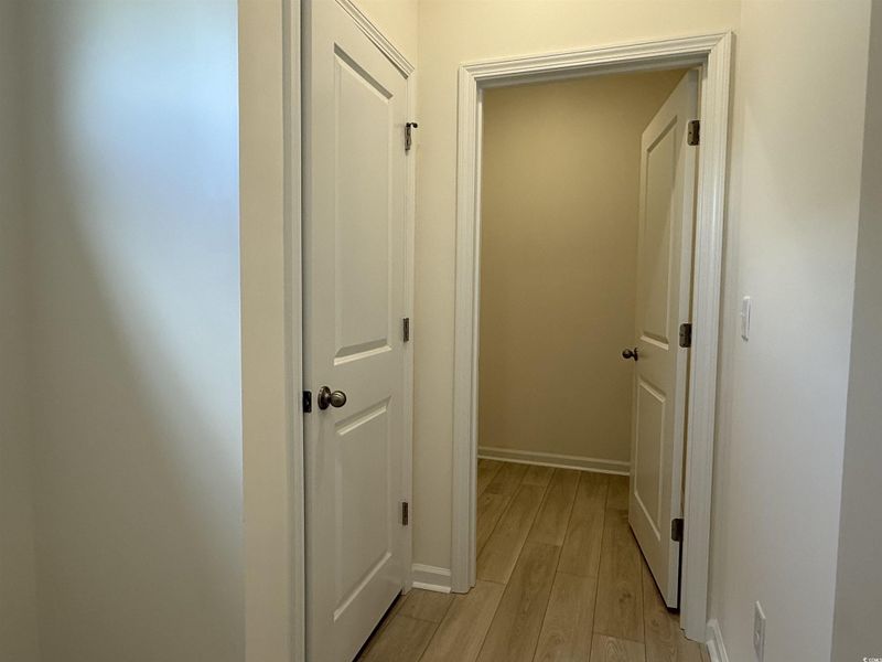 Corridor featuring light wood-style flooring and baseboards Corridor featuring light wood-style flooring and baseboards
