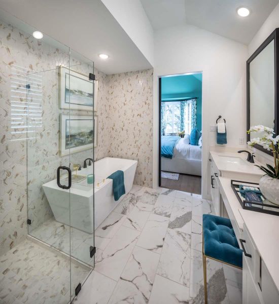 Ensuite bathroom featuring vanity, a freestanding tub, vaulted ceiling, marble finish floor, and connected bathroom