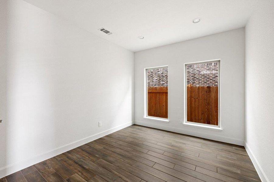 Sun-filled room boasts high ceilings and stylish tile flooring, offering a versatile space for living or working.