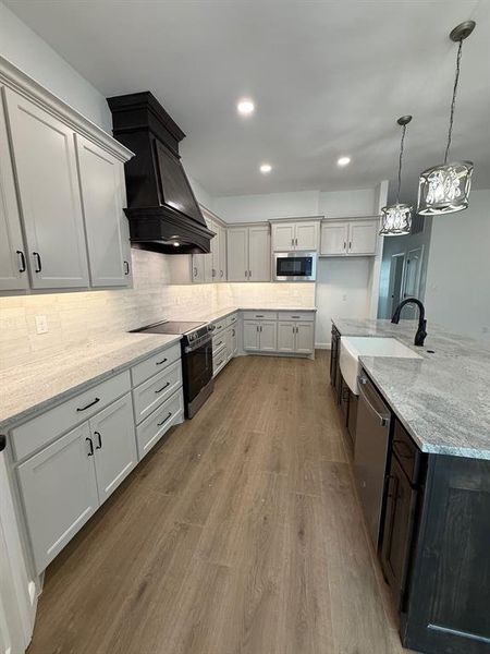 Kitchen featuring light stone countertops, range, recessed lighting, backsplash, and hanging light fixtures