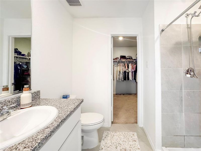Full bathroom with a walk in closet, vanity, a stall shower, and light tile patterned flooring