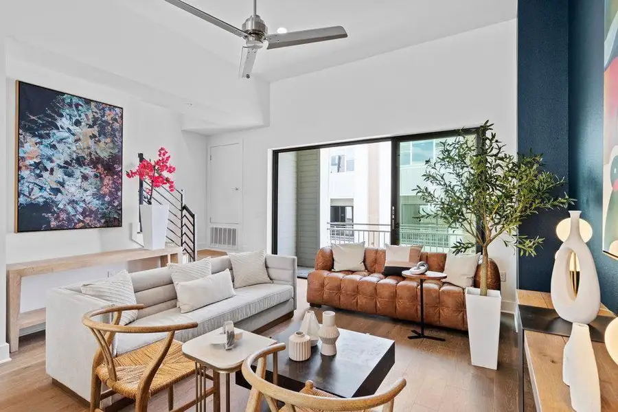 Living room featuring light wood-style flooring, a ceiling fan, and a high ceiling